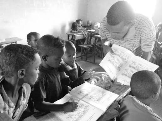 A teacher helps students read from their workbooks in a classroom at Tsegaye Berhe Woldu High School.